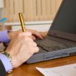 Laptop and hands with a pen