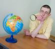 Young man with a magnifier and globe