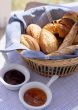 bread on a wattled tray and two cups with jam