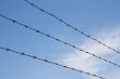 Three strands of rusty barbed wire over sky