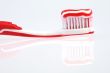 red toothbrush with toothpaste and reflection