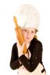 young cook wearing a chefs hat is holding a woorden rolling pin