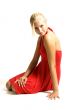 young blonde teenage girl sitting in a red dress on white