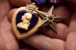 Man Holding Purple Heart and Bronze War Medals