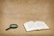 Open book and magnifier on canvas