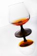 Glass of cognac standing on mirror table.