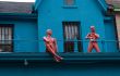 Two pink dolls at the balcony of blue howse