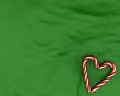 Heart made from christmas candies on green background
