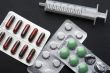 Medical tablet and syringe on black