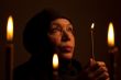 Senior Woman in black clothes with candle.