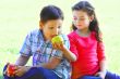 The boy with the girl play sitting on a grass