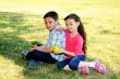 The boy with the girl play sitting on a grass