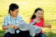 The boy with the girl play sitting on a grass