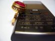 Mobile phone and golden ring with red stone