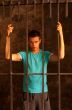 Man with hands tied with rope behind the bars