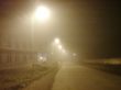 Fog laying over town. Street lamps in mist