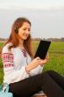 Young lady with e-book reader sitting on grass