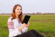 Young lady with e-book reader sitting on grass