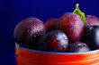 Plums. Fresh ripe washed plums in a ceramic bowl close-up on a b