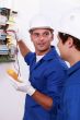 Two electricians testing fuse box