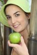 Woman stood by wooden poles holding a green apple