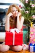 Christmas woman near a Christmas tree holding big gift box.