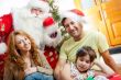 Happy family embracing and sitting on the floor in front of Christmas Tree.