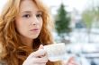 Portrait of beautiful red hair girl drinking coffee on winter ba