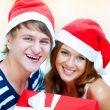 Young happy couple in Christmas hats standing together and holdi