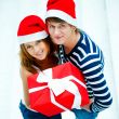 Young happy couple in Christmas hats standing together and holdi