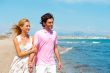Couple at the beach holding hands and walking. Sunny day, bright
