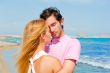 Portrait of young couple in love embracing at beach and enjoying