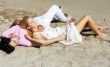 Young couple lying together on a sand by sea and looking to a sk