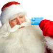 Traditional Santa Claus holding and sowing credit card while giv