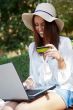 Young elegant woman wearing straw hat and white dress holding cr