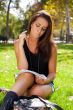 Portrait of a beautiful young female student sitting outdoor at 