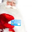 Traditional Santa Claus holding and sowing credit card while giv