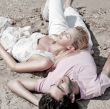 Young couple relaxing on sand at beach and daydreaming with thei