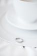 Closeup photo of proposal ring on white plate of coffee cup and 