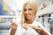 Portrait of young pretty smiling woman eating cake at shopping m