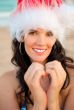 Young beautiful woman wearing christmas hat showing heart shape 