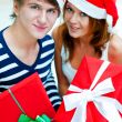 Young happy couple in Christmas hats standing together and holdi