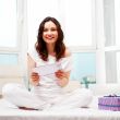 Happy woman reading a letter in her bedroom. She recieved a lett