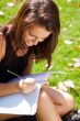 Portrait of a beautiful young female student sitting outdoor at 