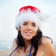 Young beautiful woman wearing christmas hat showing heart shape 