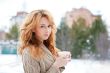 Portrait of young pretty red hair woman with cup of hot coffee o