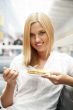 Portrait of young pretty smiling woman eating cake at shopping m
