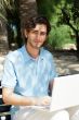 Portrait of a young man with laptop outdoor sitting on bench
