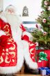 Santa sitting at the Christmas tree, fireplace and looking at ca