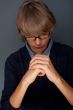 Young man praying against grey background